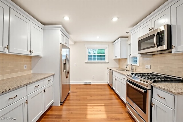 kitchen with white cabinetry, stainless steel appliances, baseboards, and visible vents