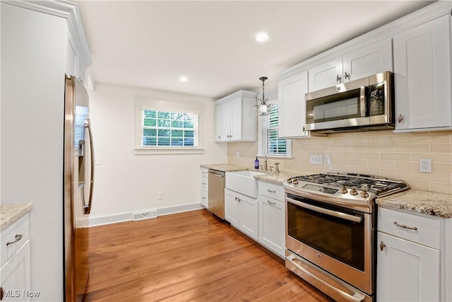 kitchen featuring white cabinetry, stainless steel appliances, tasteful backsplash, and light wood-type flooring