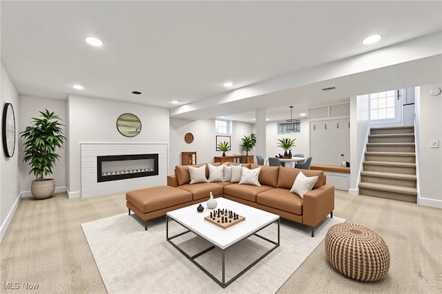 living area featuring baseboards, stairway, recessed lighting, and light colored carpet