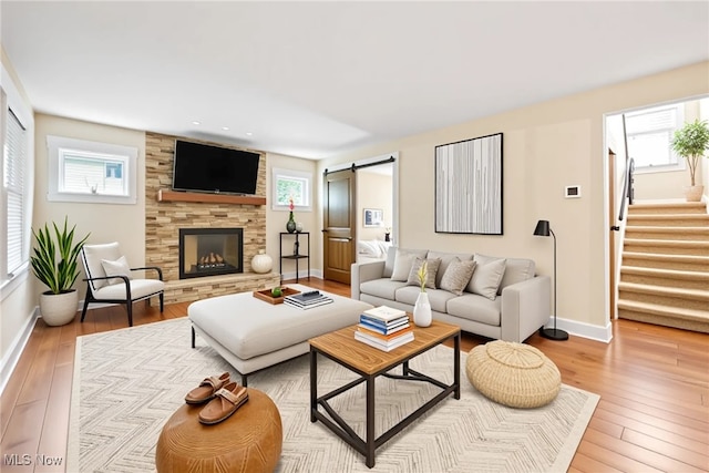 living area with a barn door, light wood-type flooring, and baseboards