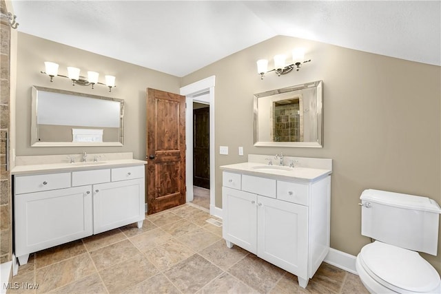 full bath featuring lofted ceiling, two vanities, toilet, and a sink