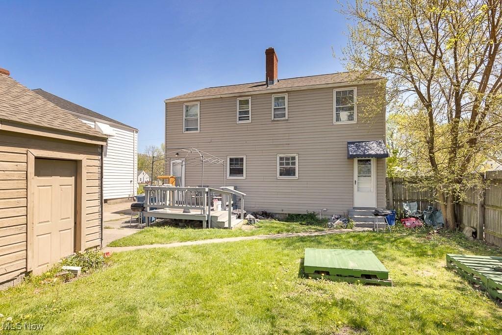 back of house featuring a wooden deck, fence, a lawn, and entry steps