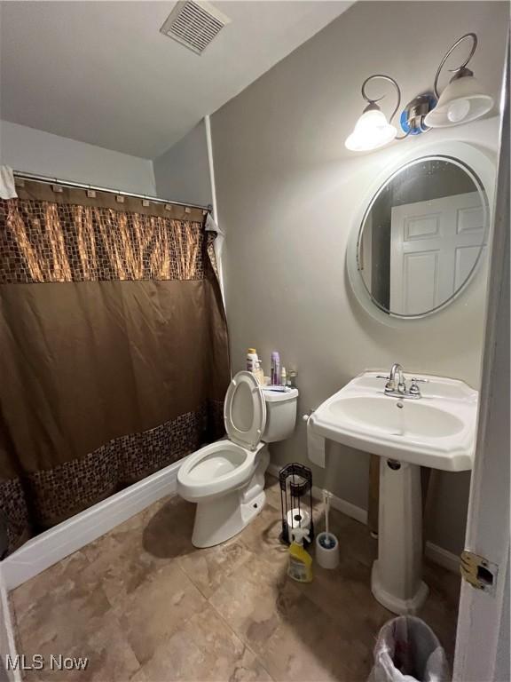 bathroom featuring toilet, visible vents, baseboards, and a shower with shower curtain