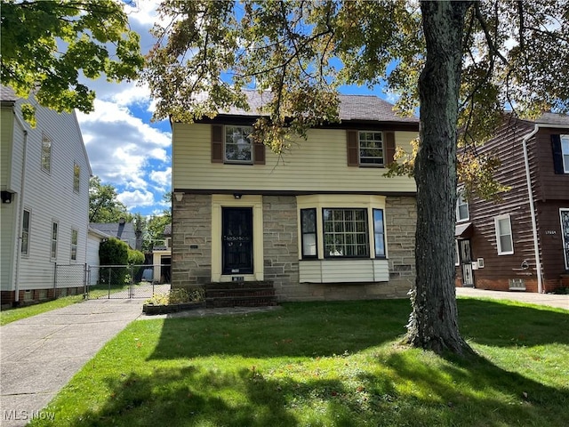 colonial house with stone siding, fence, and a front yard