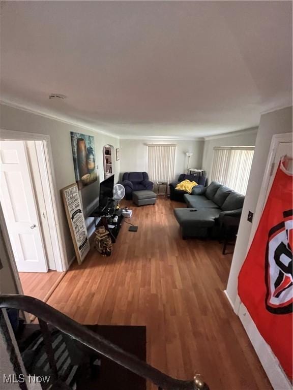 living area featuring crown molding, arched walkways, and wood finished floors