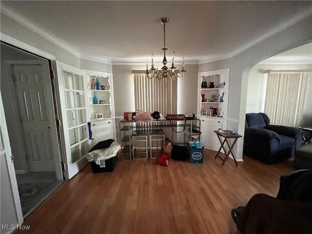 dining area featuring ornamental molding, an inviting chandelier, wood finished floors, and arched walkways