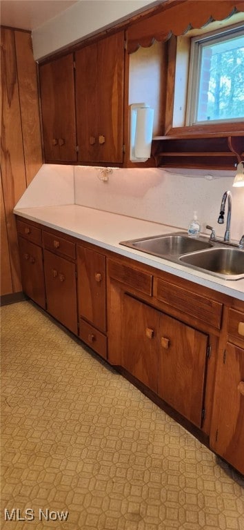 kitchen featuring brown cabinets, light countertops, light floors, and a sink