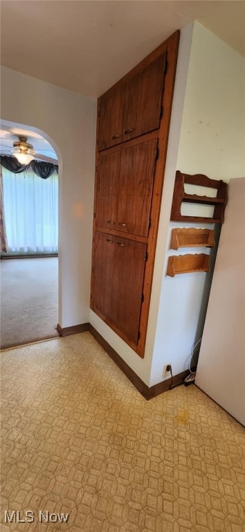 spare room with light floors, arched walkways, and baseboards