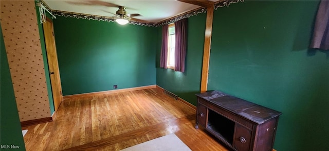 unfurnished room featuring baseboards, visible vents, ceiling fan, and wood finished floors