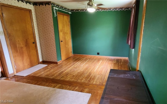 spare room with wood finished floors, baseboards, and ceiling fan