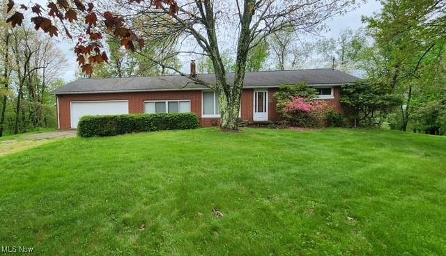 ranch-style home with brick siding, a garage, a chimney, and a front yard