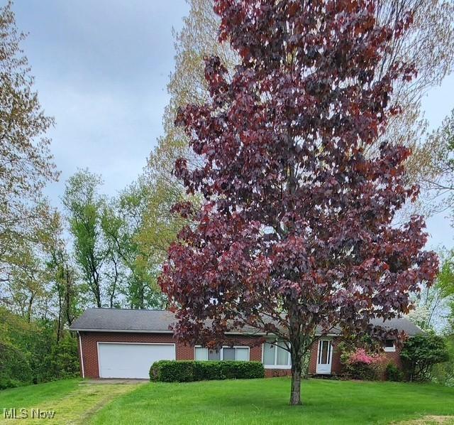 obstructed view of property featuring brick siding, a front lawn, and a garage