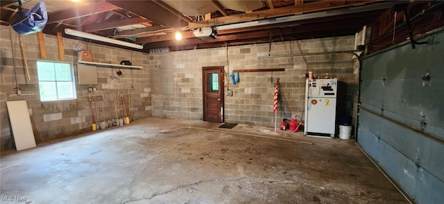 garage featuring freestanding refrigerator, concrete block wall, and a garage door opener