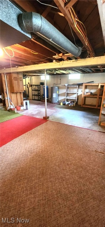 unfinished below grade area featuring carpet flooring and electric water heater