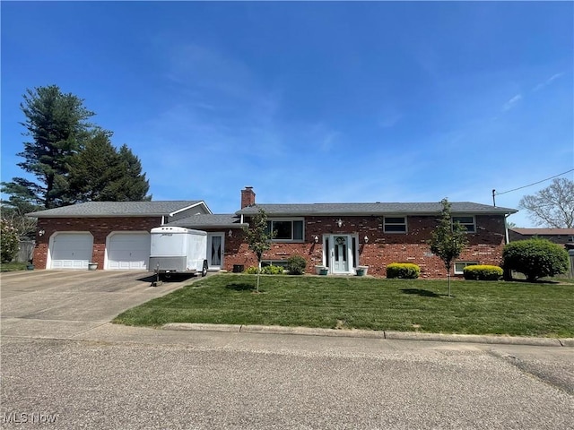 bi-level home with an attached garage, brick siding, concrete driveway, a front yard, and a chimney