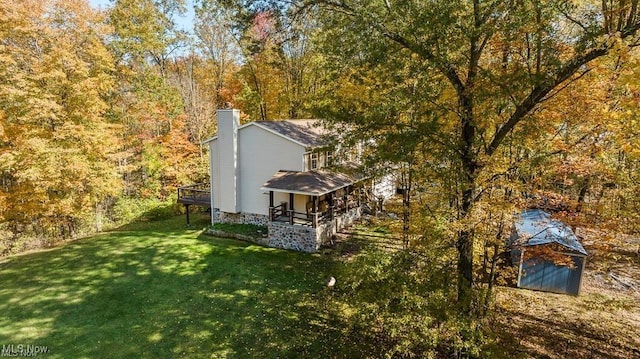 13109 Edison St NE, Alliance, OH 44601 - view of home's exterior featuring a porch, a wooded view, a chimney, and a lawn