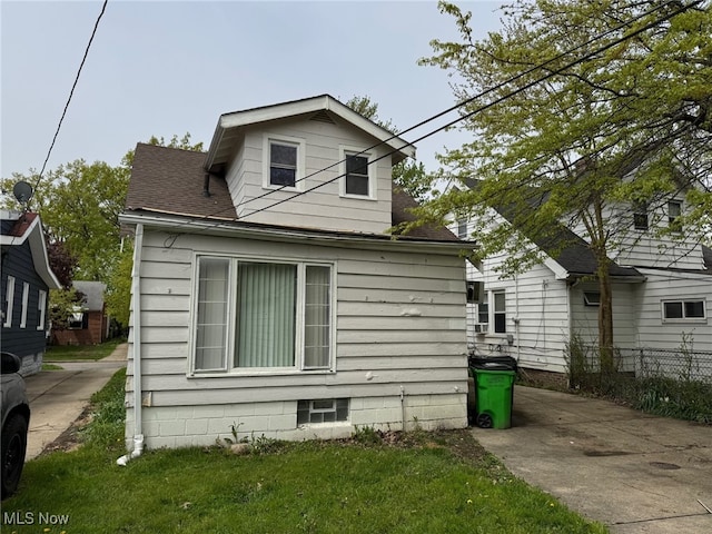 view of side of property with a shingled roof and fence