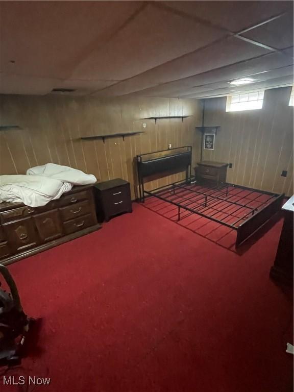 bedroom featuring a wood stove, carpet flooring, and wood walls