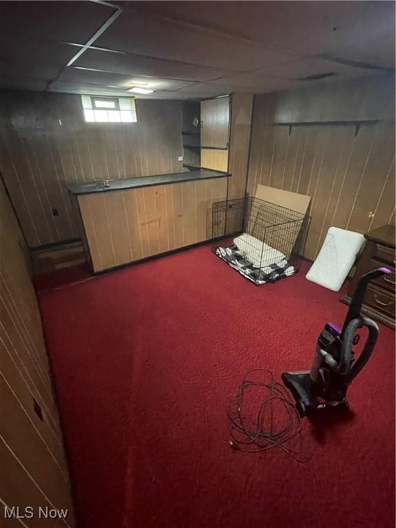 basement featuring a dry bar, wooden walls, and carpet floors