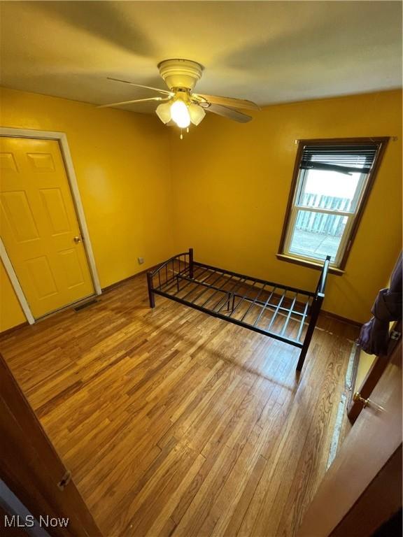 unfurnished room with baseboards, a ceiling fan, and wood finished floors