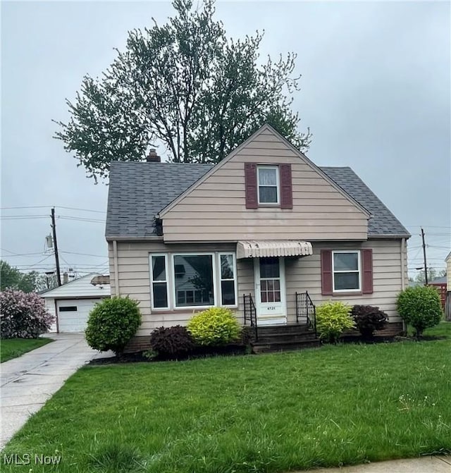 bungalow-style house featuring roof with shingles, an outbuilding, a front yard, and a detached garage