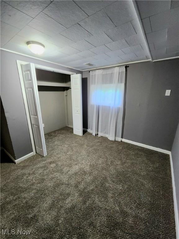 unfurnished bedroom with baseboards, carpet flooring, and a closet