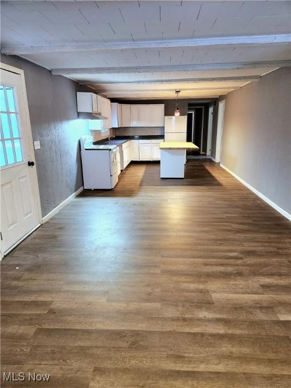 kitchen with freestanding refrigerator, pendant lighting, white cabinetry, beamed ceiling, and baseboards