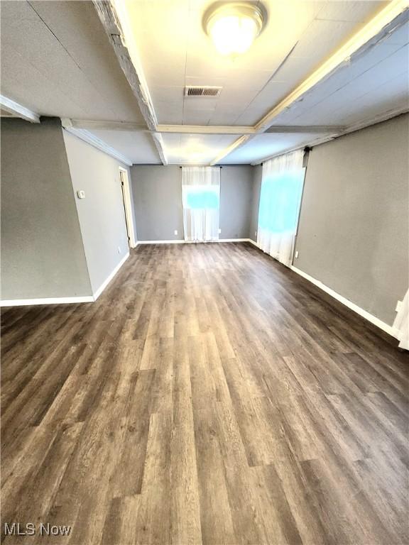 basement featuring baseboards, visible vents, and wood finished floors