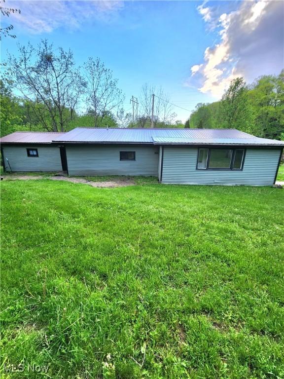 rear view of property with a yard and metal roof