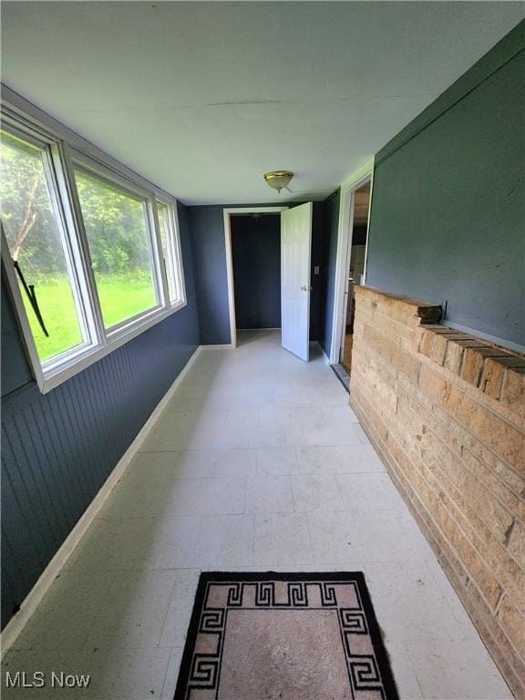 corridor featuring light floors and baseboards