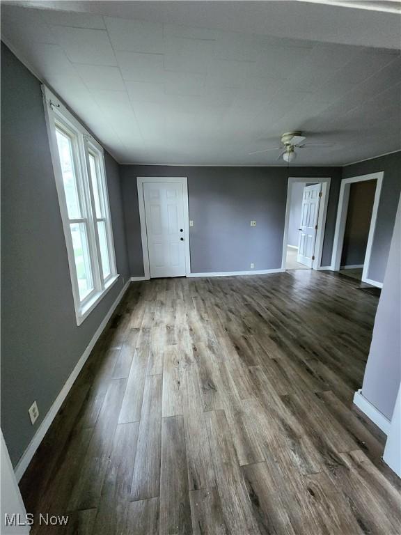 unfurnished room featuring dark wood-type flooring, baseboards, and ceiling fan