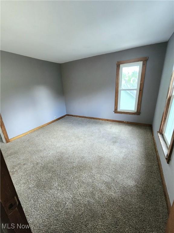 spare room featuring carpet floors, baseboards, and plenty of natural light