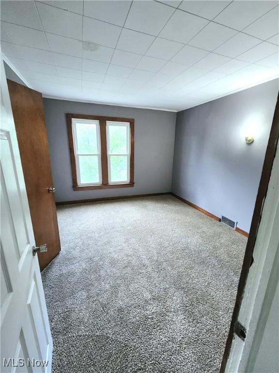 carpeted empty room featuring visible vents and baseboards