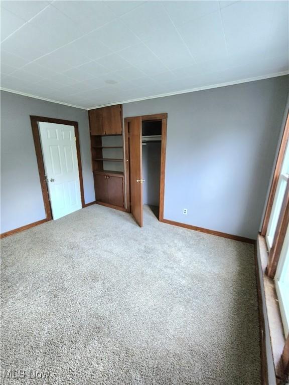 unfurnished bedroom with light colored carpet, baseboards, and ornamental molding