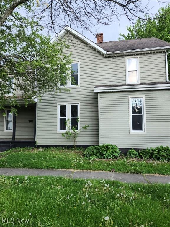 view of side of property with a yard and a chimney