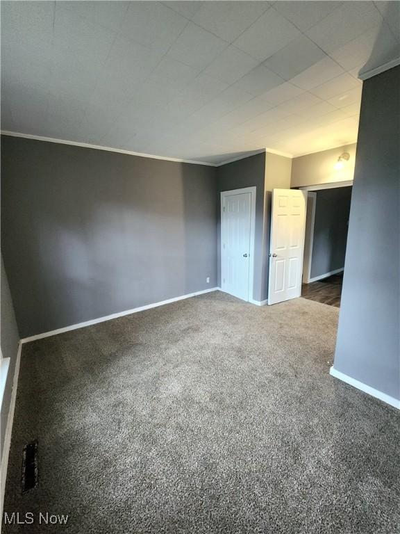 carpeted empty room with crown molding and baseboards