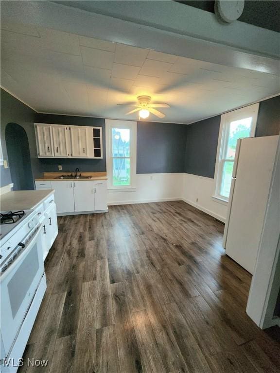 kitchen with white appliances, white cabinets, dark wood-style flooring, ceiling fan, and arched walkways