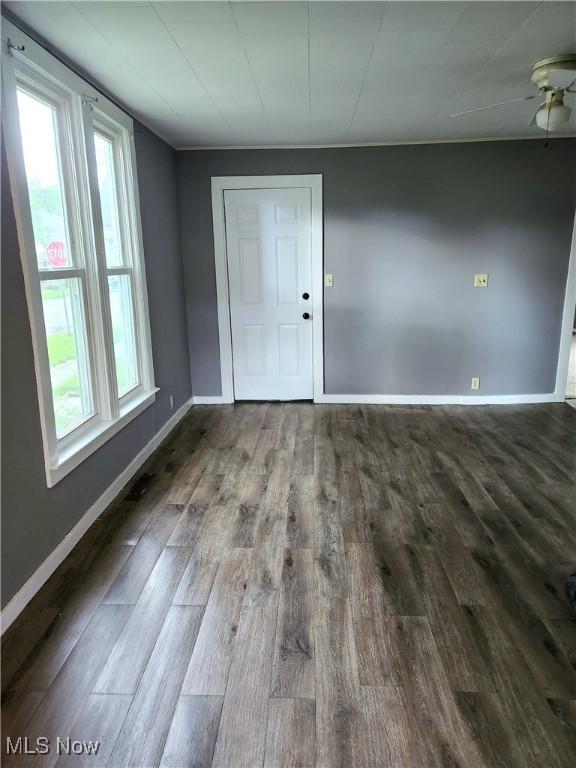 empty room with baseboards, ceiling fan, and wood finished floors