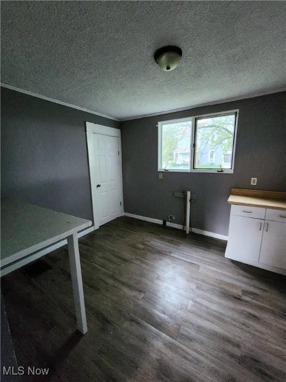 unfurnished dining area with dark wood finished floors, baseboards, and a textured ceiling