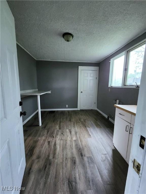 washroom with a textured ceiling, dark wood-type flooring, and baseboards