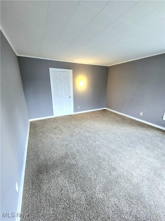 unfurnished room featuring ornamental molding, carpet, and baseboards