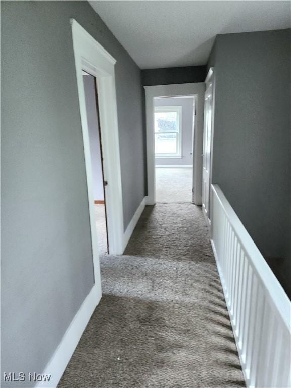 hallway featuring carpet and baseboards