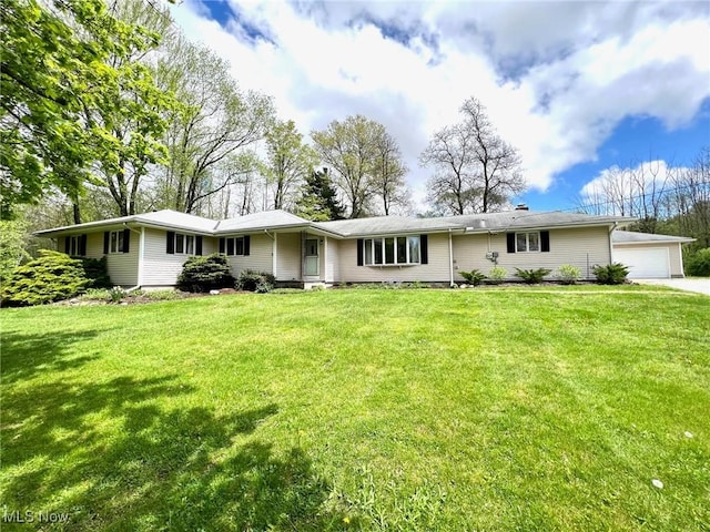 rear view of property with a garage and a lawn