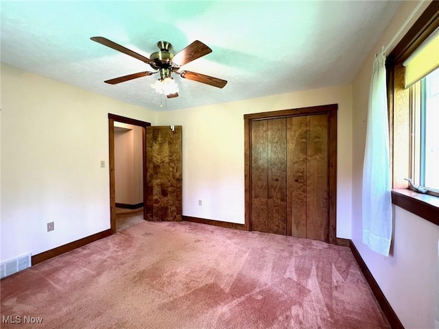 unfurnished bedroom with a closet, carpet, baseboards, ceiling fan, and visible vents