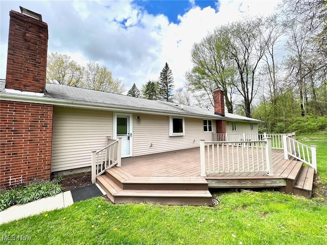 back of property featuring a yard, a chimney, and a wooden deck