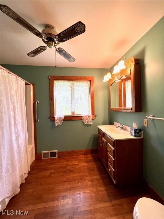 bathroom featuring wood finished floors, a ceiling fan, visible vents, baseboards, and vanity