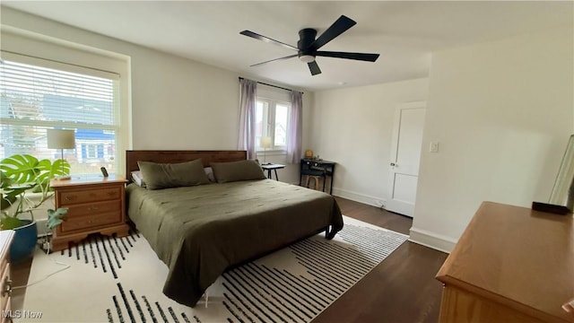 bedroom featuring baseboards, wood finished floors, and a ceiling fan