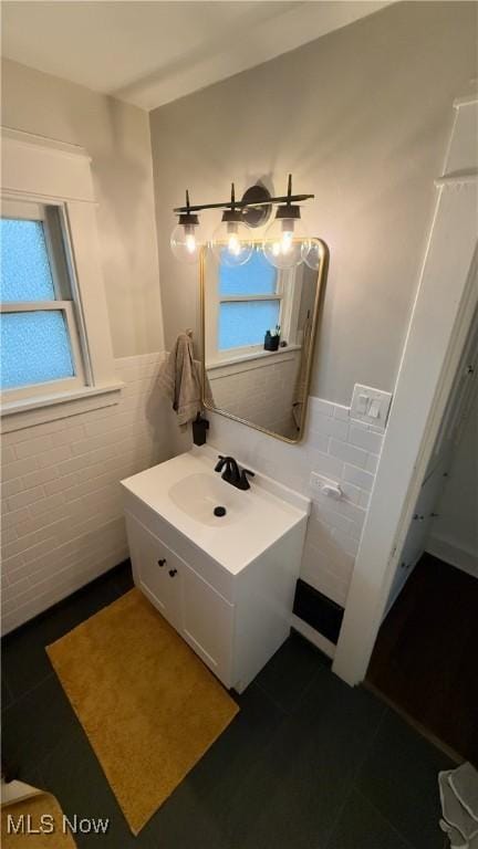 bathroom with vanity, tile walls, a wainscoted wall, and plenty of natural light