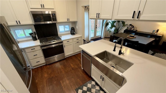 kitchen with stainless steel appliances, dark wood finished floors, white cabinetry, light countertops, and a wealth of natural light