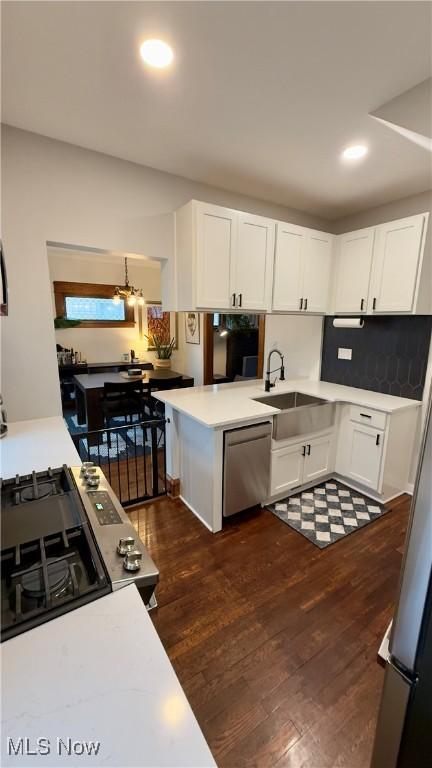 kitchen featuring a peninsula, white cabinetry, stainless steel dishwasher, and a sink